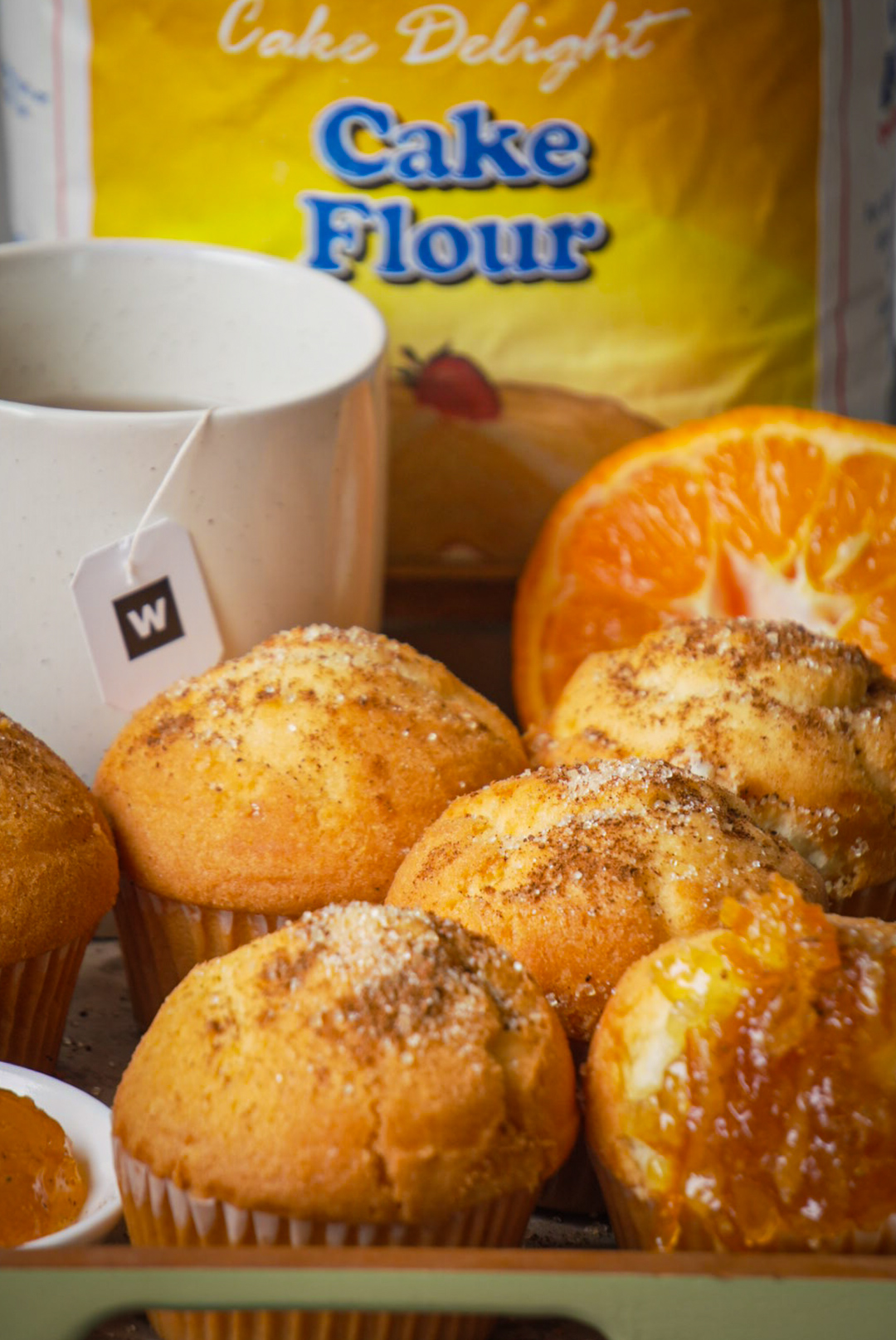 Cinnamon sugar doughnut muffins styled with fresh orange and Cake Delight flour packaging